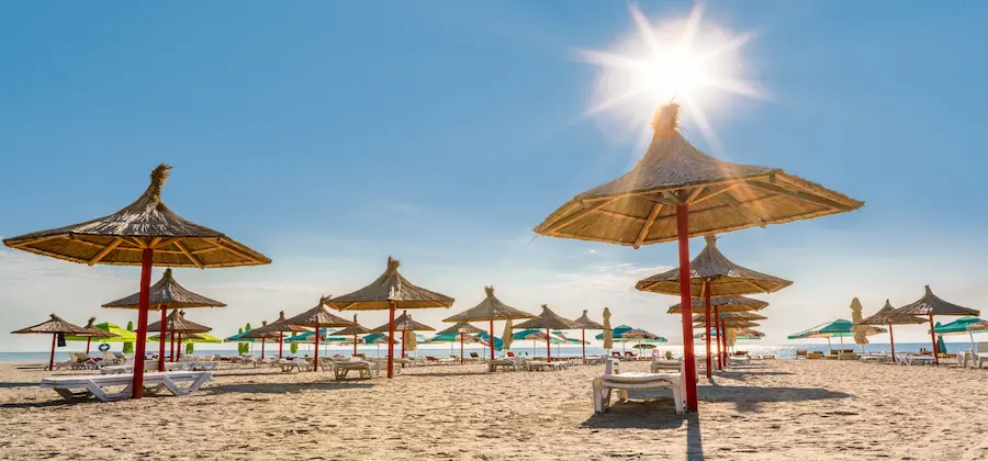 Umbrele din paie și șezlonguri sub soarele puternic pe plaja Mamaia, litoral românesc - oferte hoteluri TravelTheme