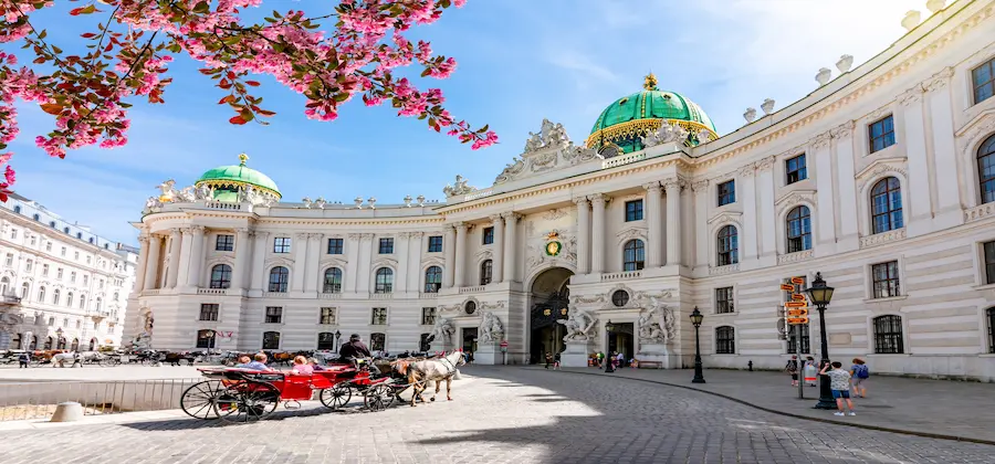 Trăsură cu cai pe caldarâm lângă Michaelertrakt, cireși roz înfloriți, escapadă Viena Austria - oferte hoteluri
