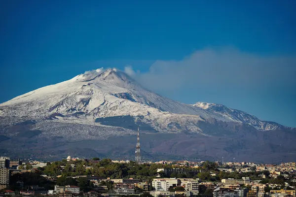Varful inzapezit al vulcanului Etna cu fum deasupra orasului Catania Sicilia