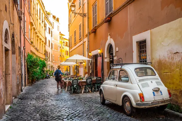 Stradela pietruita din cartierul Trastevere cu Fiat 500 si terasa, Roma, Italia